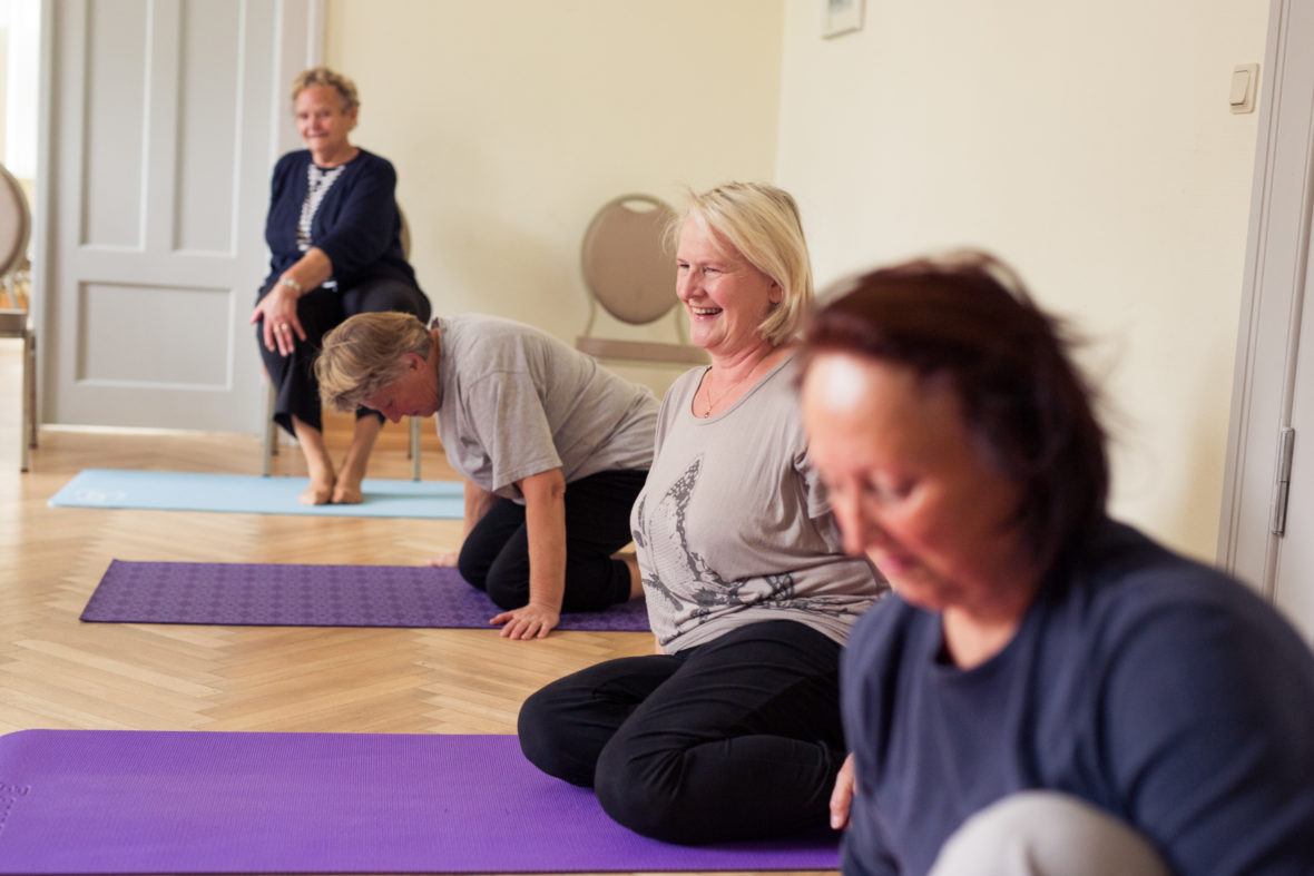 Die Seniorinnen sitzen auf ihren Yogamatten.