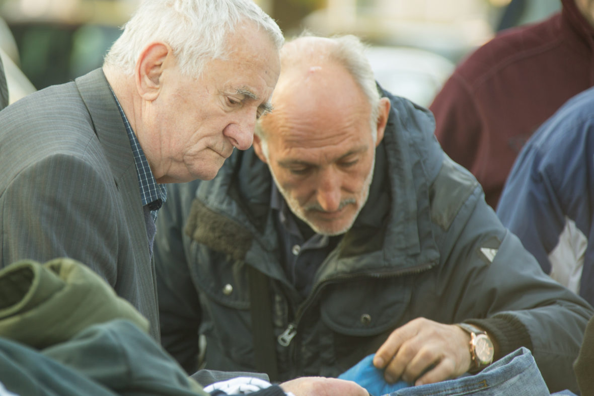 Zwei obdachlose Männer suchen sich Kleidungsstücke aus.