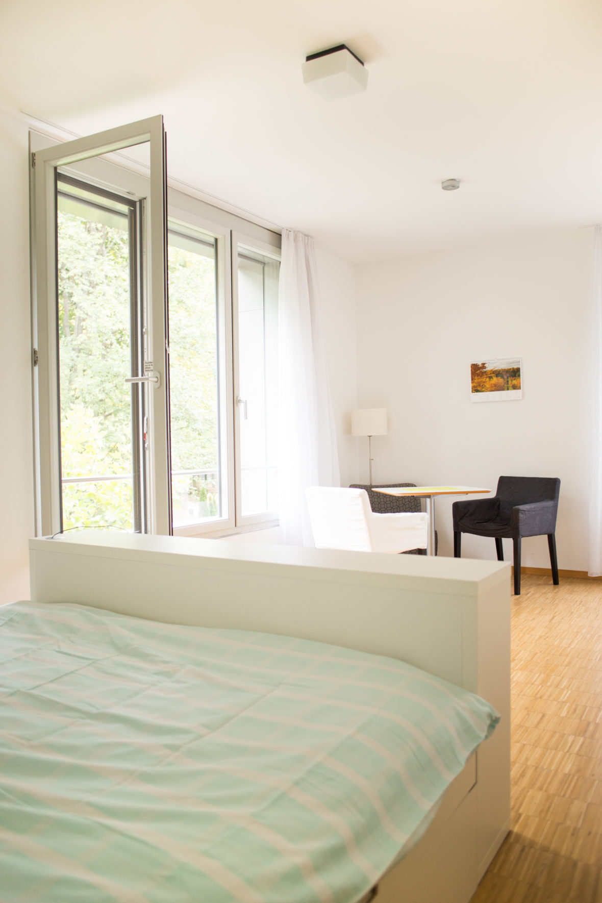 Die Zimmer sind hell und lichtdurchflutet: weiße Wände, ein weißes Doppelbett, heller Holzboden.