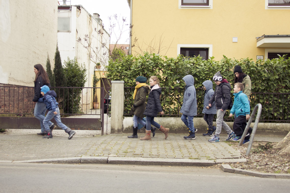 Zwei Frauen und viele Kinder gehen eine Straße entlang.
