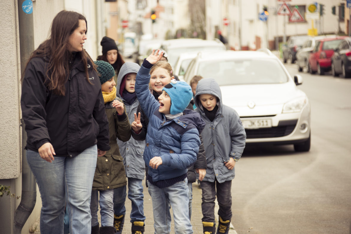Eine Frau und viele Kinder gehen eine Straße entland.