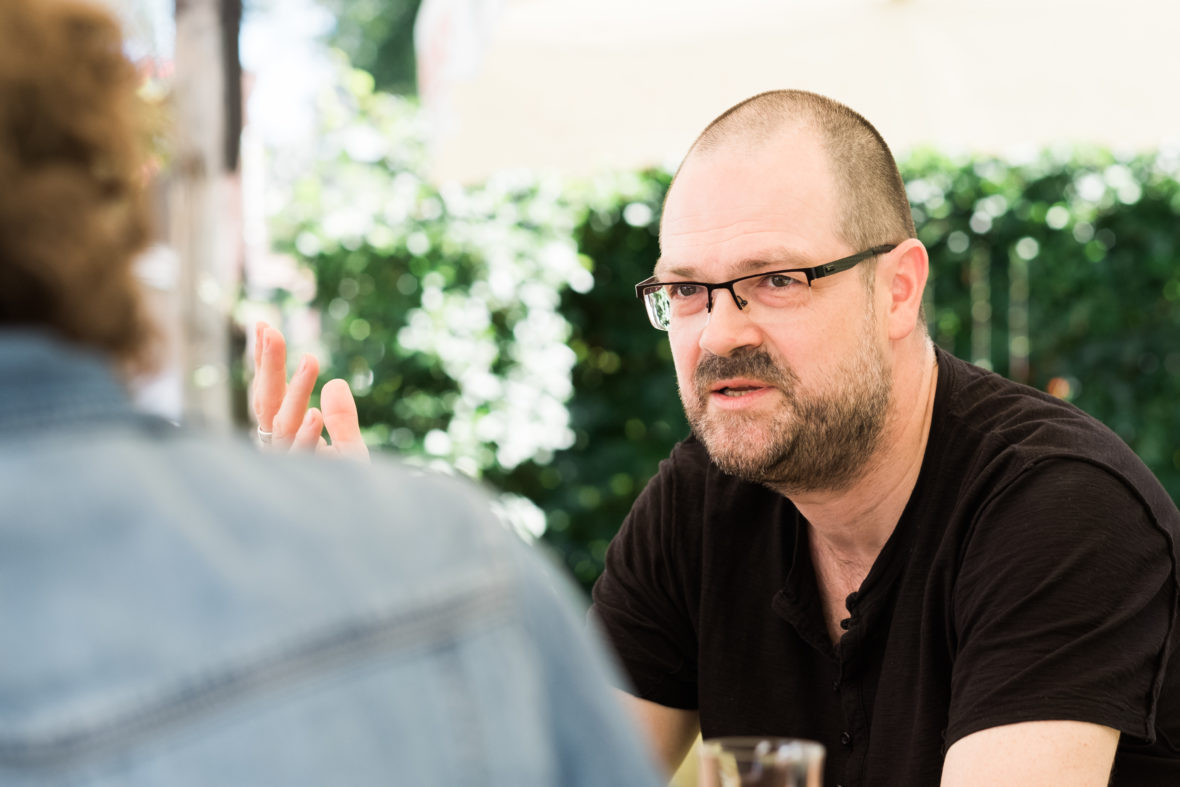 Ein Mann mittleren Alters mit einer Brille gestikuliert beim Sprechen.
