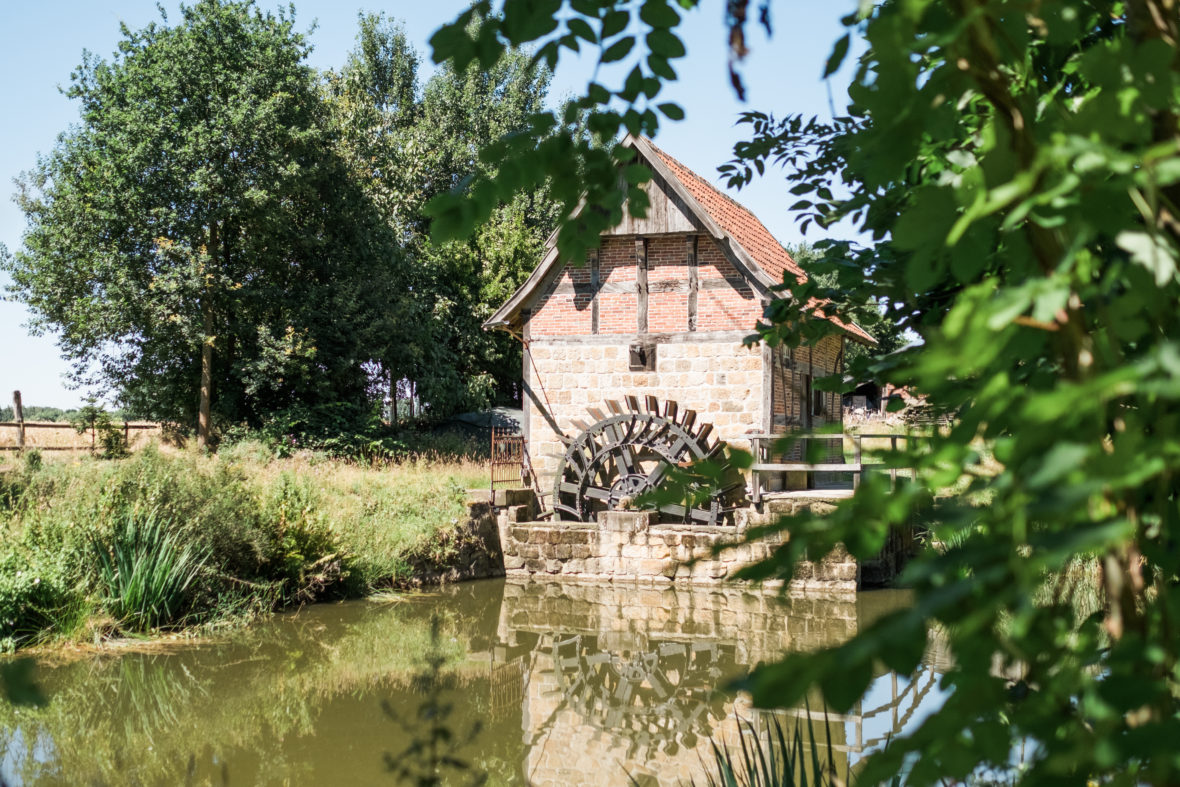 Eine alte Mühle mit Mühlrad an einem Weiher.