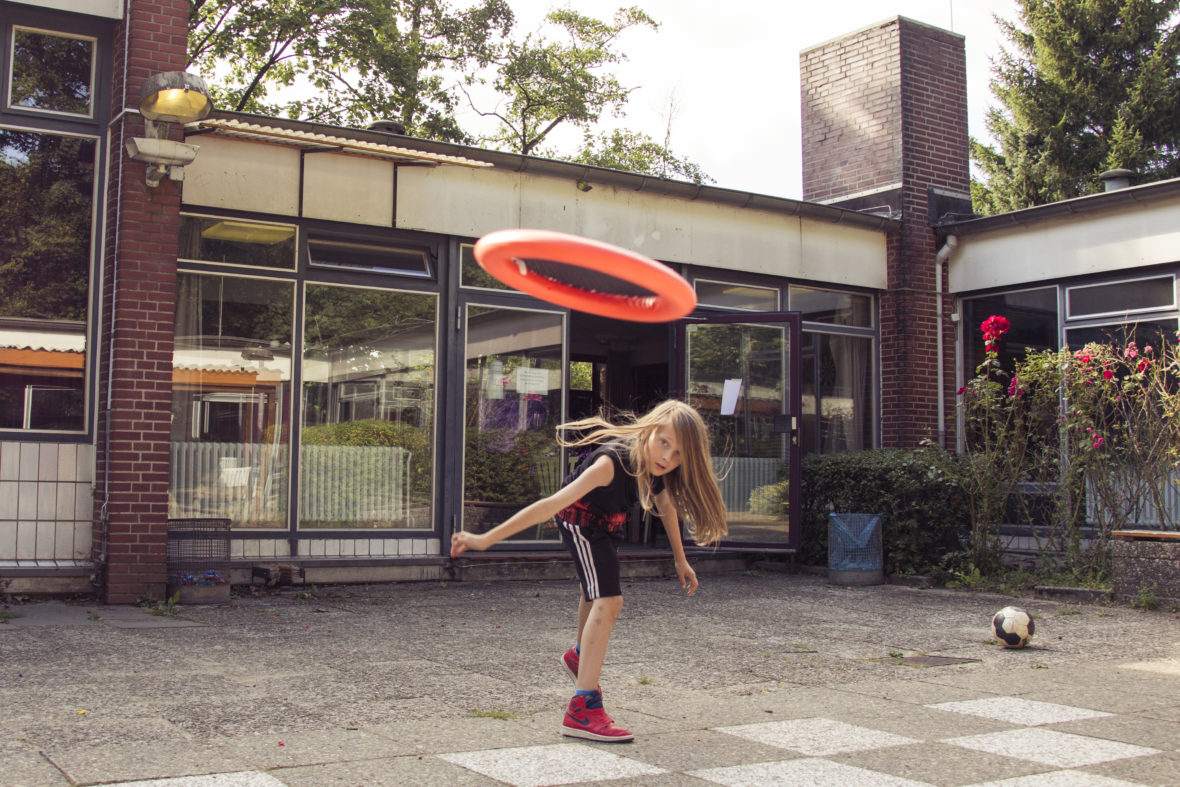 Ein Junge mit langen Haaren wirft ein Frisbee.