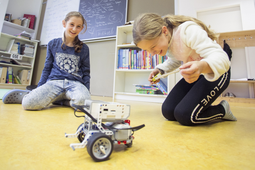 Mädchen spielen im Klassenraum mit ihrem Roboter.