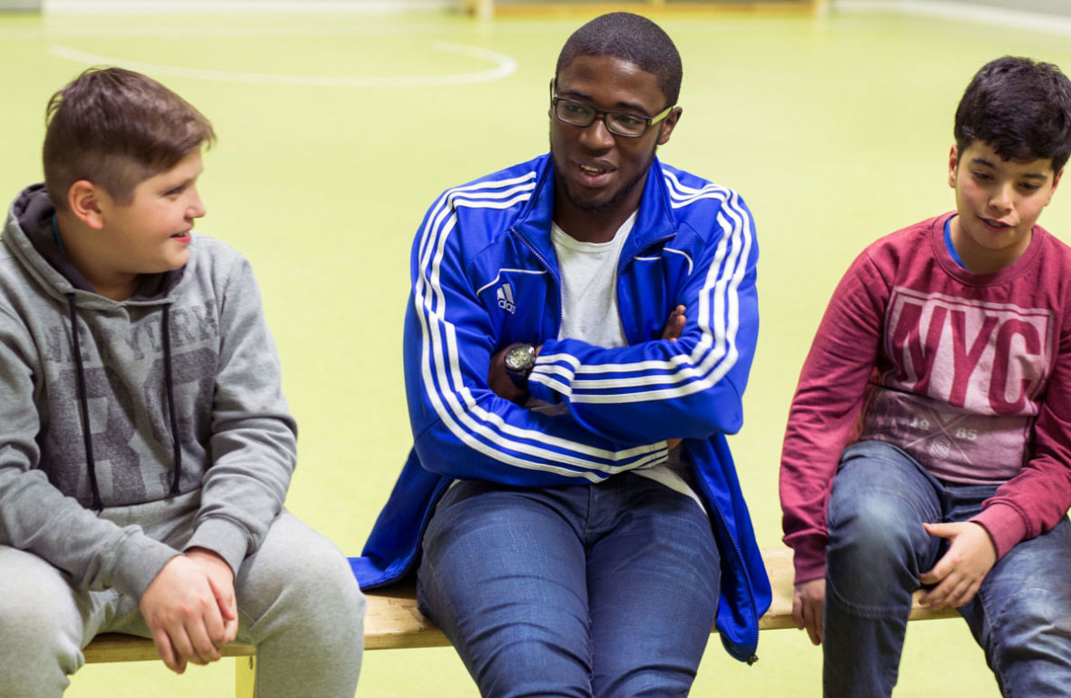 Zwei Jungs sprechen mit dem ehrenamtlichen Trainer Henry Barker