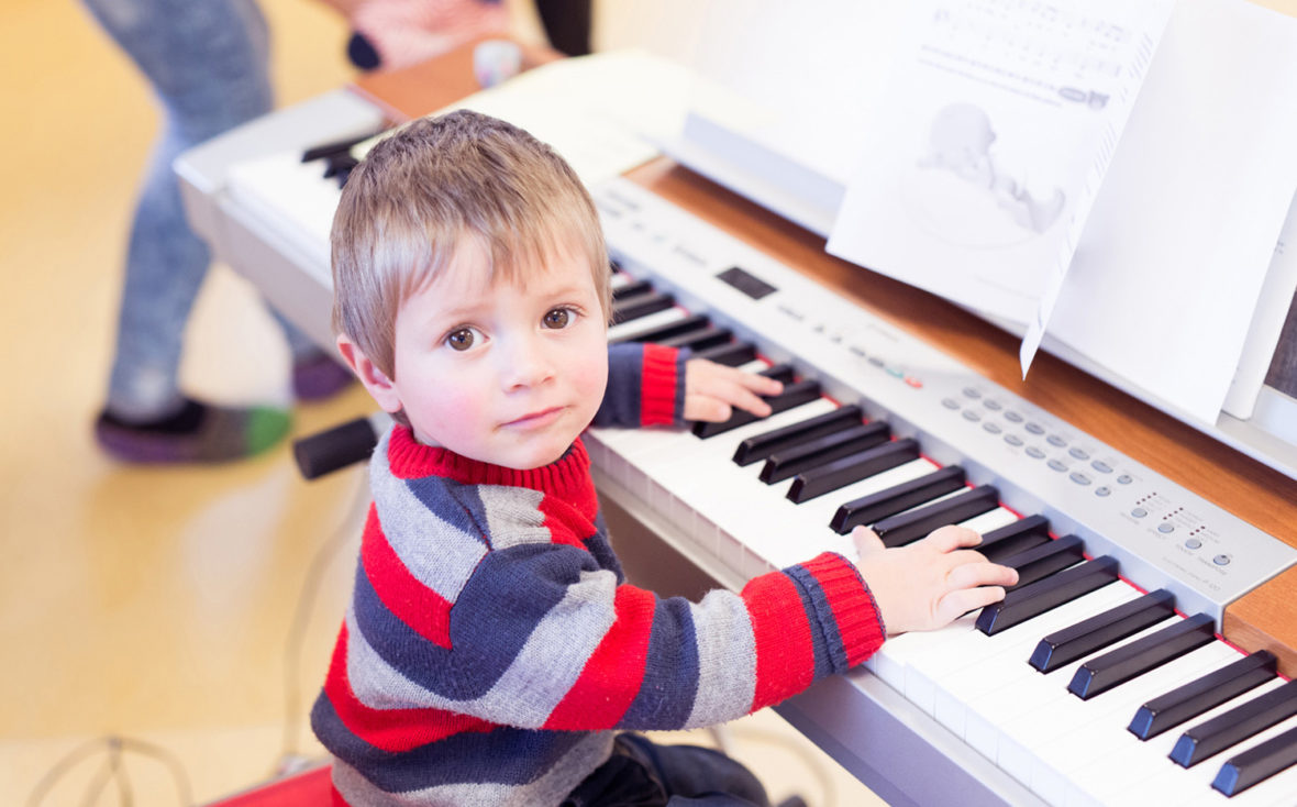 Kleiner Junge sitzt am Klavier.