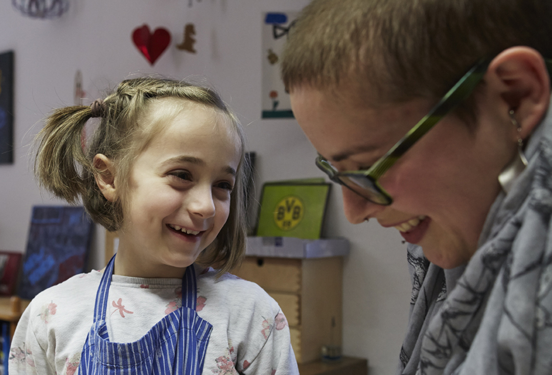 Ein junges Mädchen lacht gemeinsam mit einer Mitarbeiterin der Kinder- und Jugendhilfe St. Mauritz.