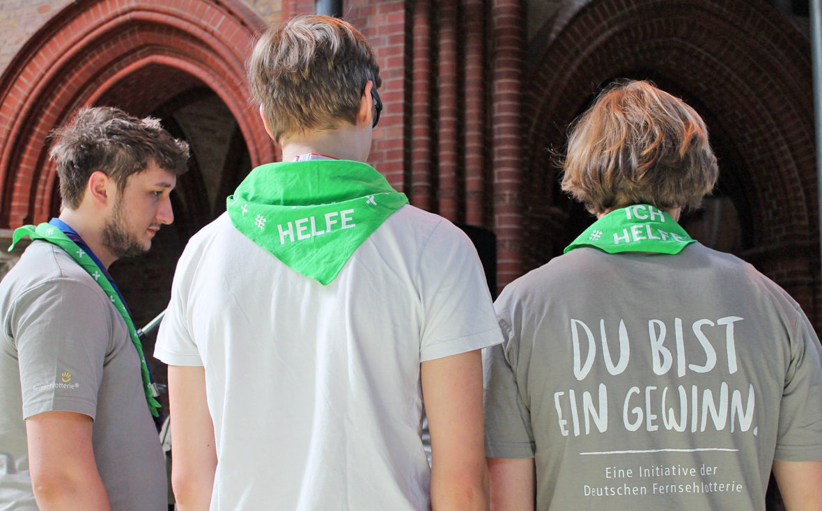 Die Jungs bei der Besprechung, man sieht den Schriftzug "Du bist ein Gewinn" auf den Shirts