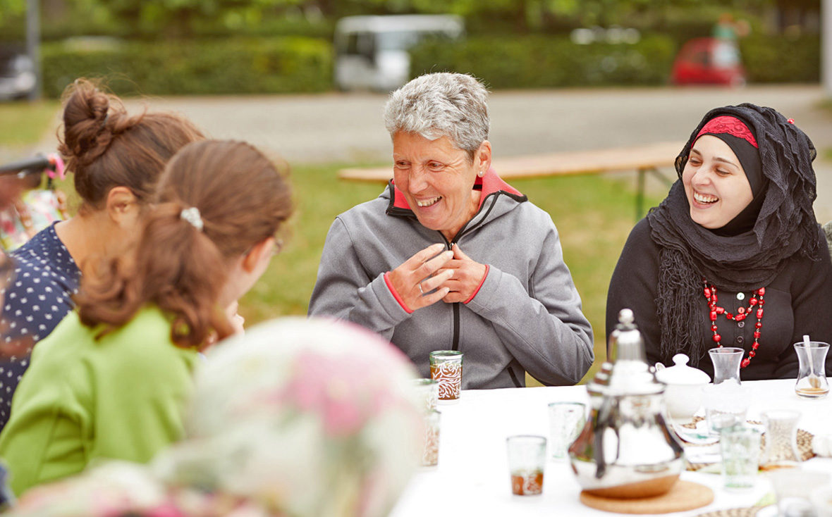 Frauen sitzen am Tisch und lachen.