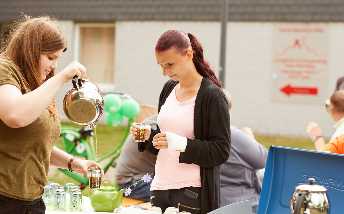 Eine Frau holt sich ein Gläschen Tee am Mobilitea-Stand.