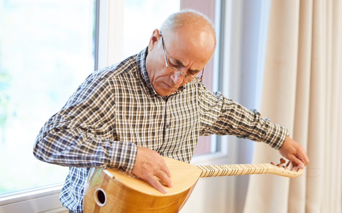 Ein Teilnehmer des Demenz-Theaters "Vergissmeinnicht" stimmt ein türkisches Saiteninstrument.