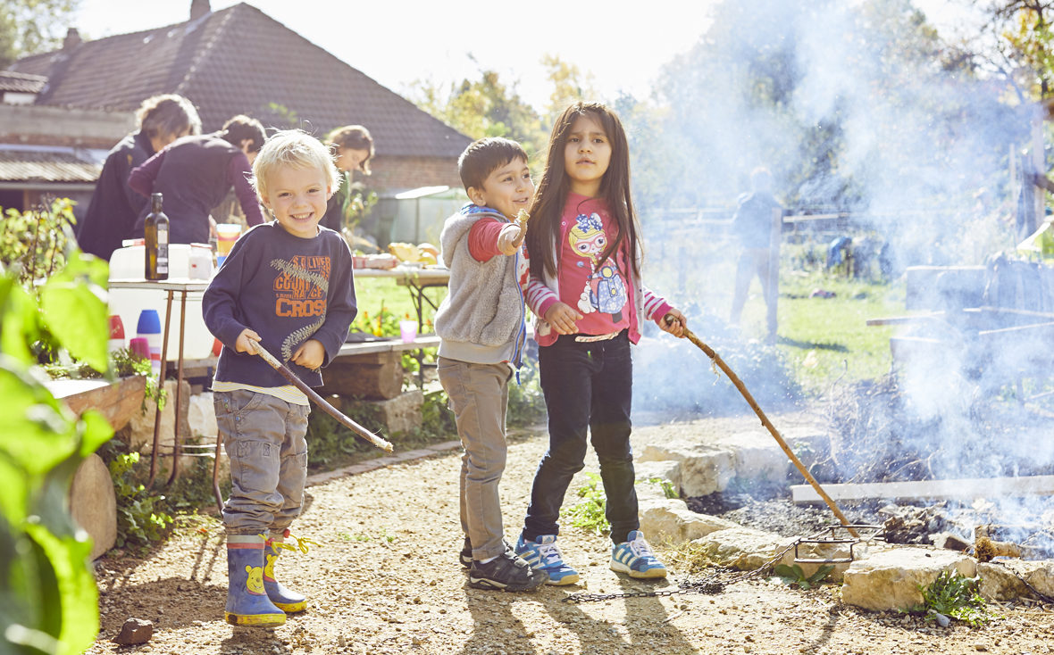 Kinder stehen am Lagerfeuer.