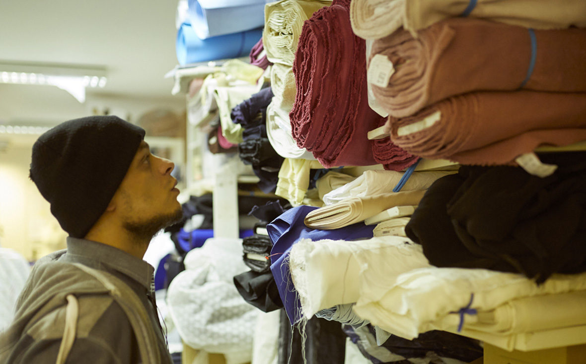 Habib schaut sich im Mode-Atelier die Stoffe an.