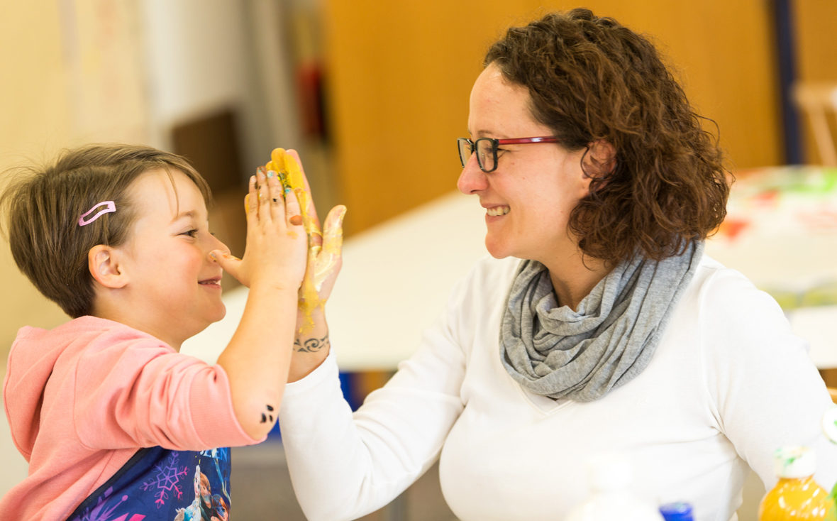 Mutter und Kind geben sich ein High Five.