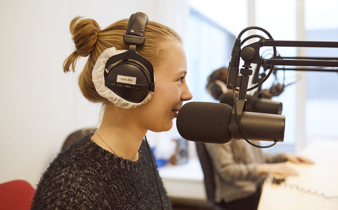 Klinikradio Rio: Eine Patientin am Mikrofon, auf den Kopfhörern steht "Radio Rio".