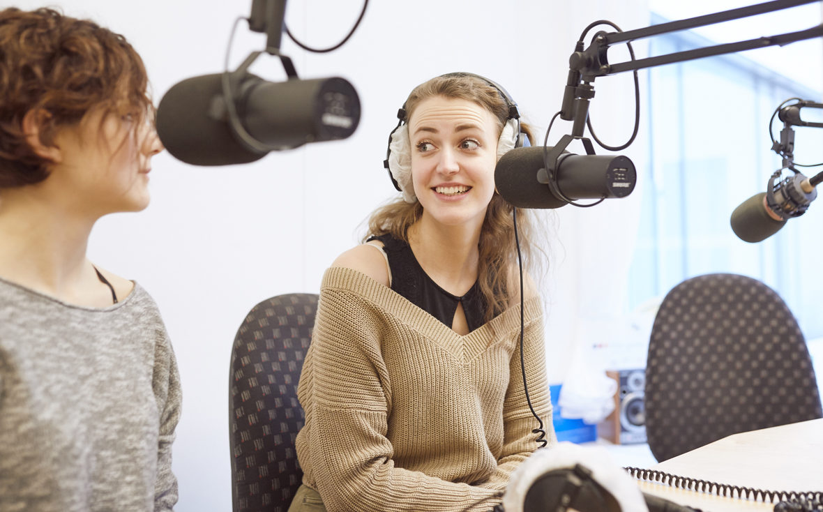Klinikradio Rio: Zwei Patientinnen sitzen vor den Mikrofonen und schauen sich an.