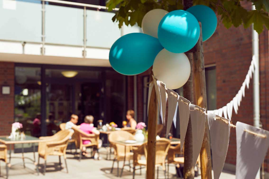 Im Garten-Café im Mehrgenerationenhaus Mathildenstift hängen Luftballons und Girlanden.