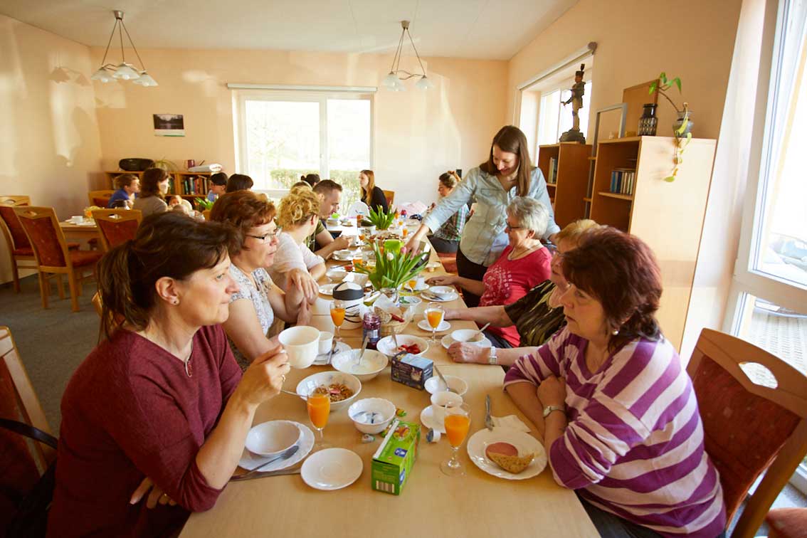 An einer langen Tafel sitzen die Nachbarn in Schwarzenberg zusammen, Quartiersmanagerin Sarah Meyer gießt Kaffee ein.