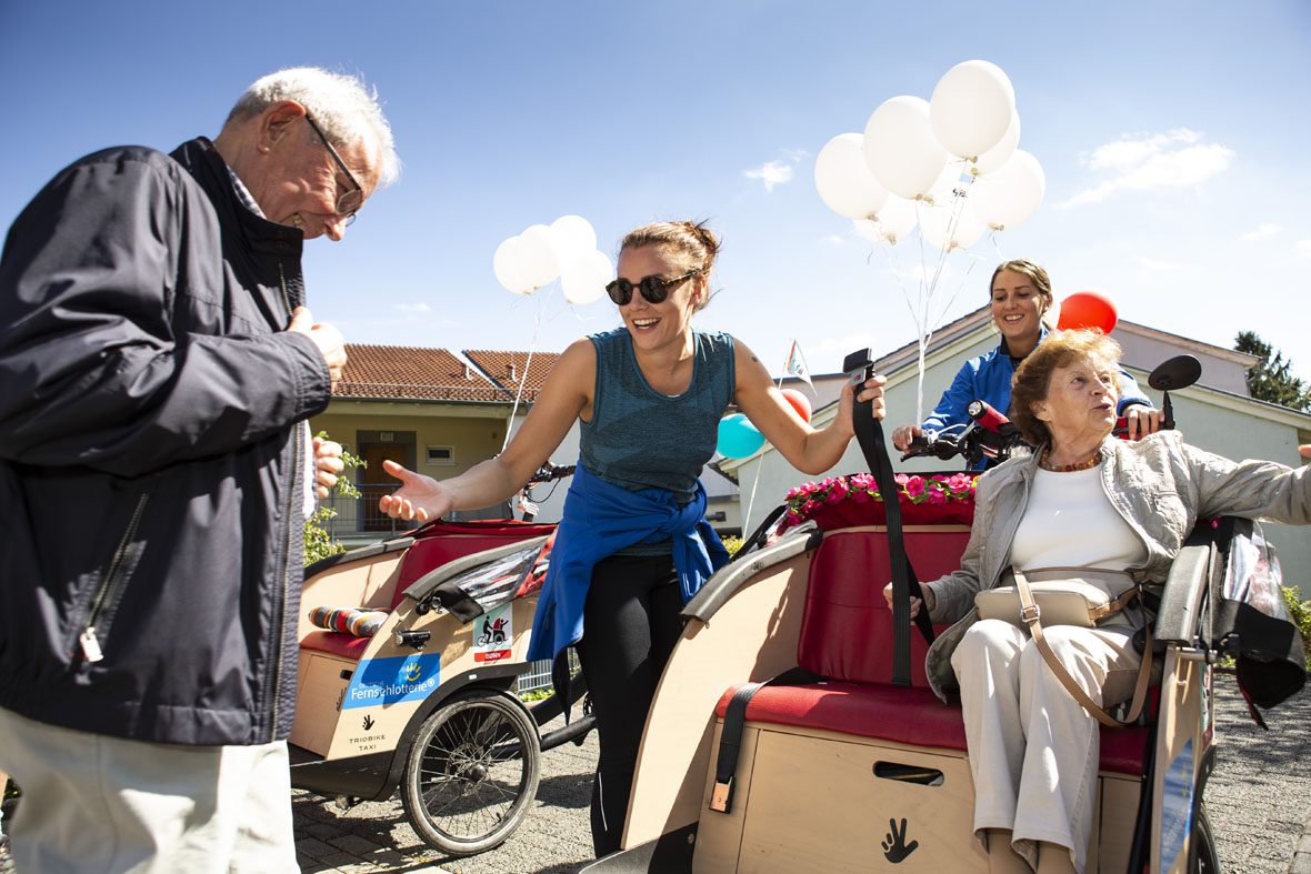 Caroline Kuhl hilft einem älteren Mann beim Einstieg in die Fahrradrikscha.