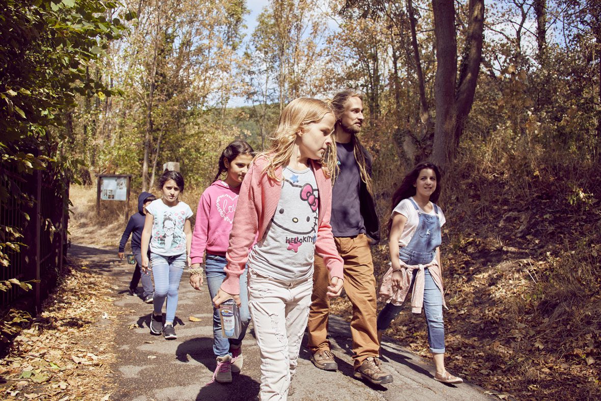 Eine Gruppe Kinder und ihr Betreuer gehen in den Wald, um Stöcke zu suchen.