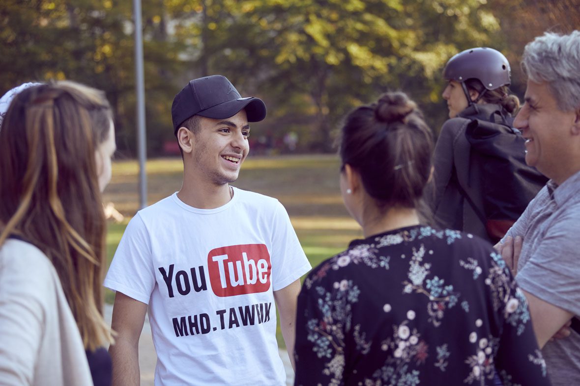 Tawfik trägt sein YouTube-Shirt und lächelt Amadeus an. Danaben stehen Denise und Natascha.