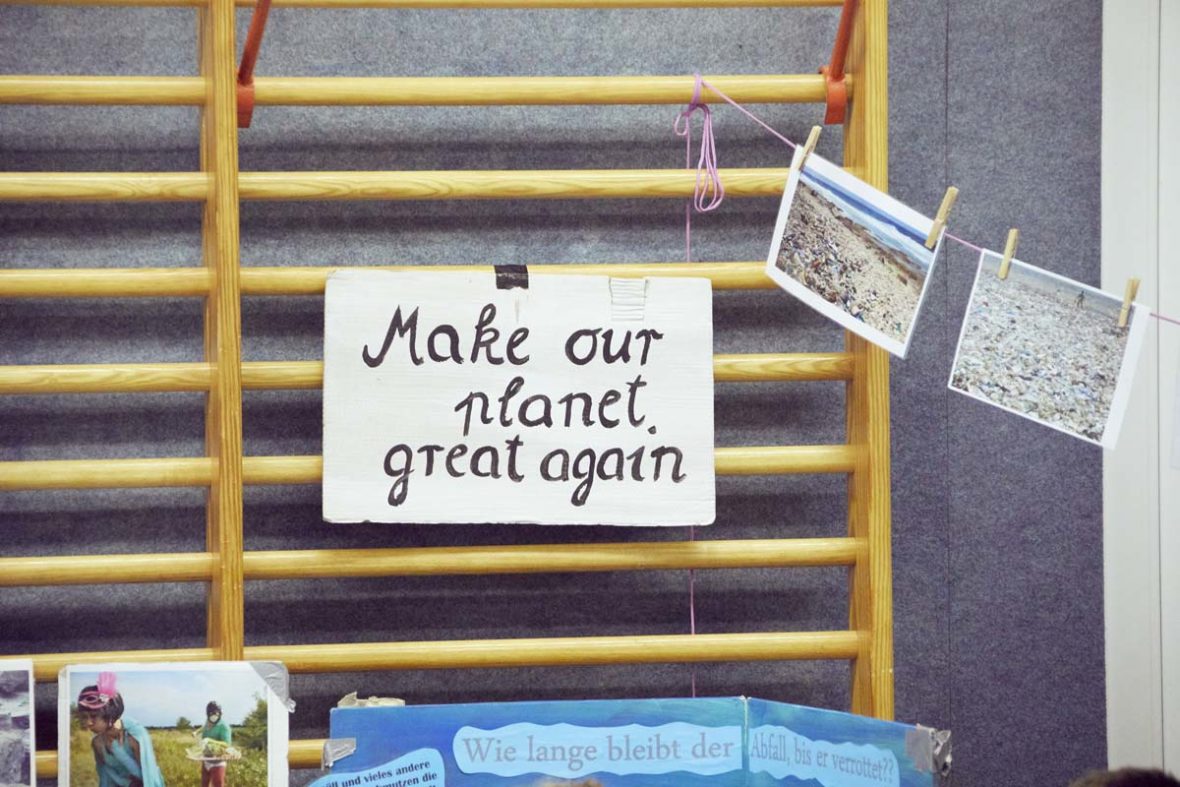 An der Kletterwand der Turnhalle hängt ein Schild mit dem Spruch: Make our planet great again.