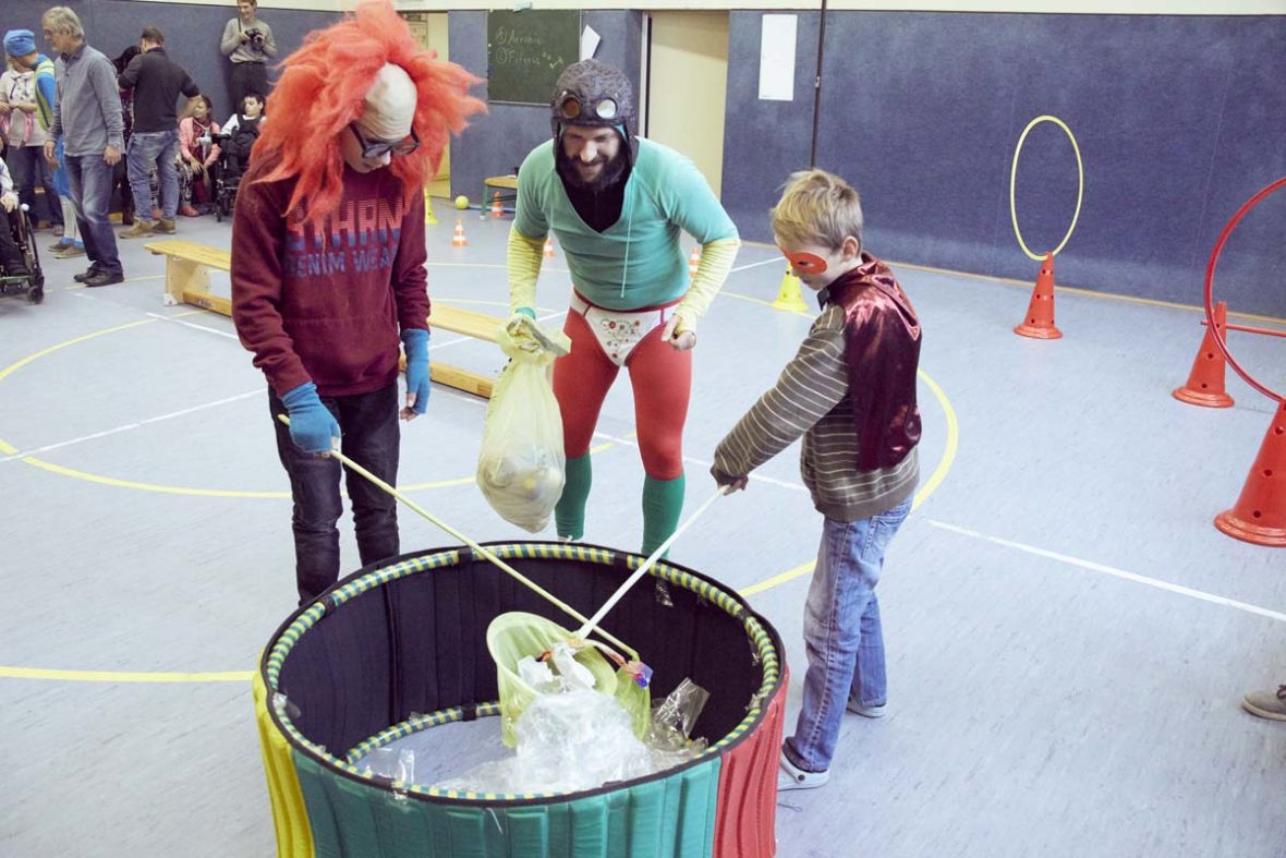 Zwei Kinder versuchen aus einem kleinen Becken, das mit Plastik gefüllt ist, Müll zu fischen.