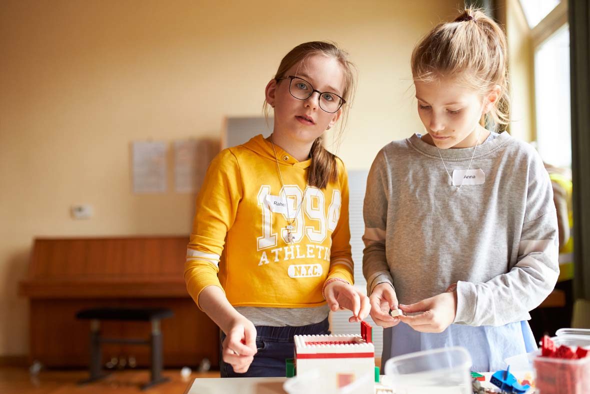 zwei Mädchen bauen an einem LEGO-Haus.