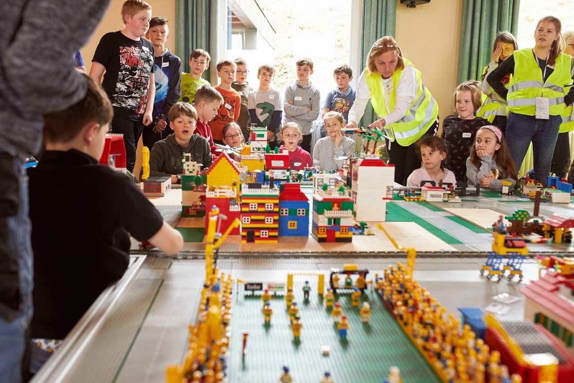 Die Kinder sitzten gemeinsam vor der von ihnen gebauten Stadt aus LEGO-Steinen.