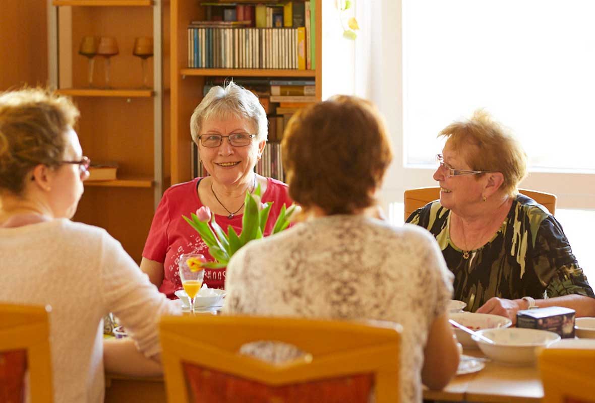 Vier Frauen sitzen am Tisch und unterhalten sich.