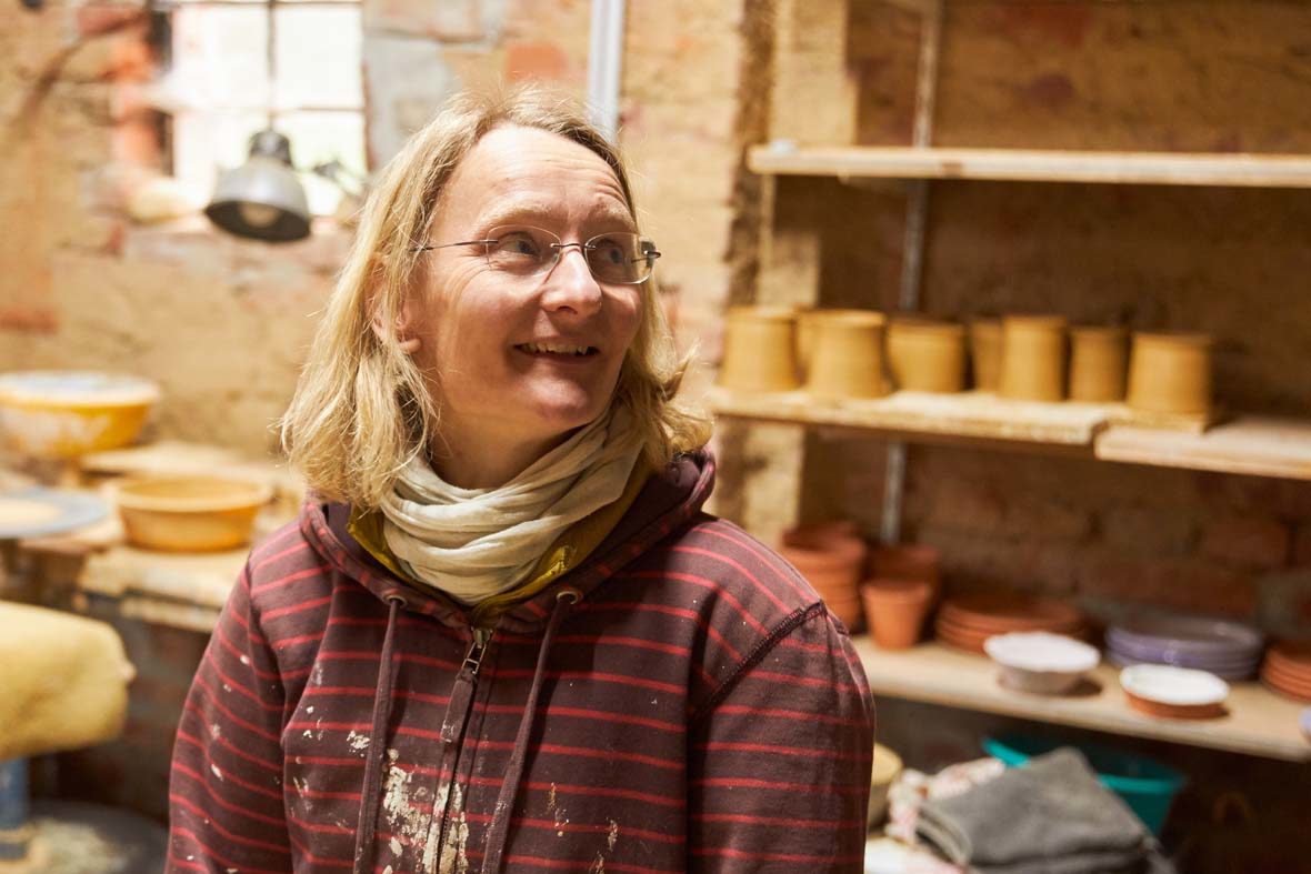 Eine Frau mit Brille steht in der Töpferei.