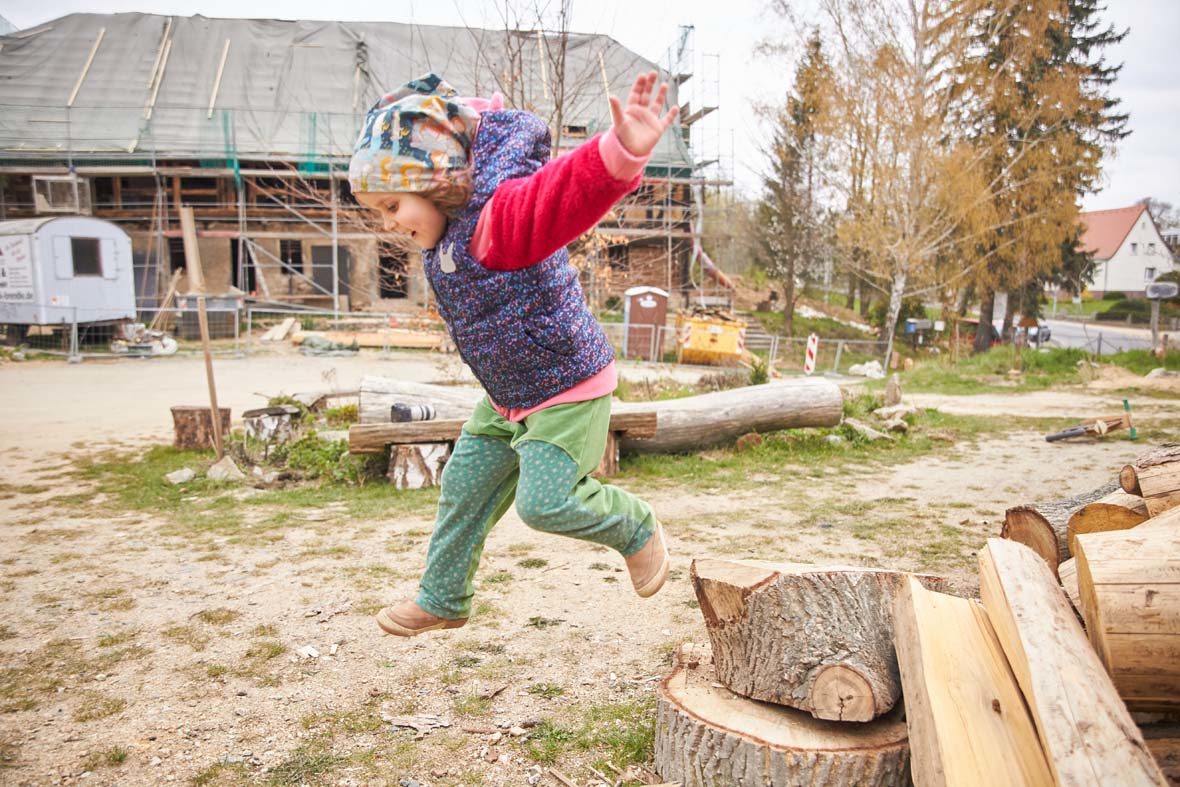 Junges Mädchen springt von einem Holzklotz.