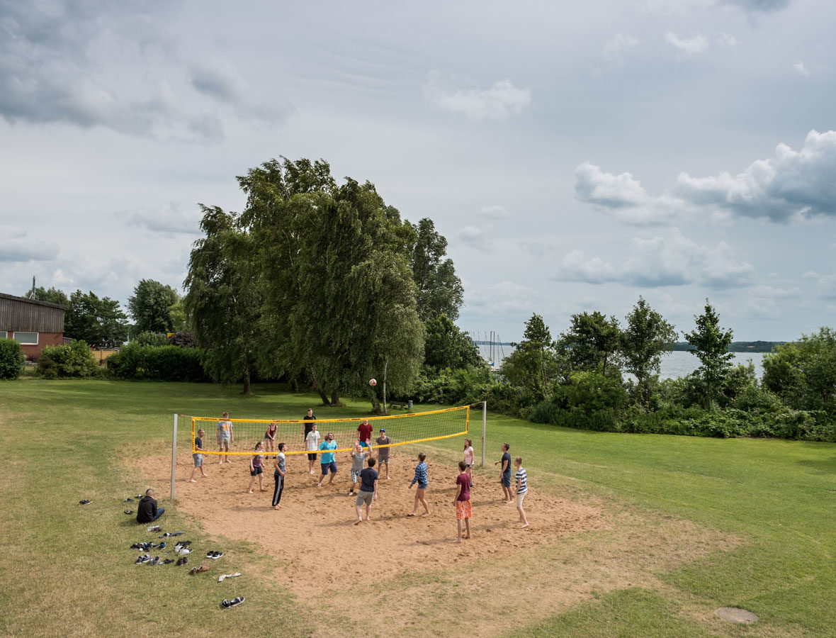 Foto: Mehrere Kinder spielen auf einem Beach-Volleyballplatz.