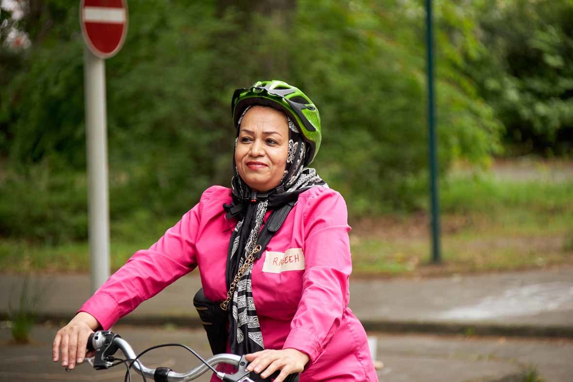 Foto: Eine Frau mit Helm fährt alleine Fahrrad und lächelt