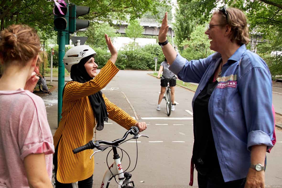 Foto: Annette Krüger schlägt mit einer Frau, die neben einem Fahrrad steht, ein