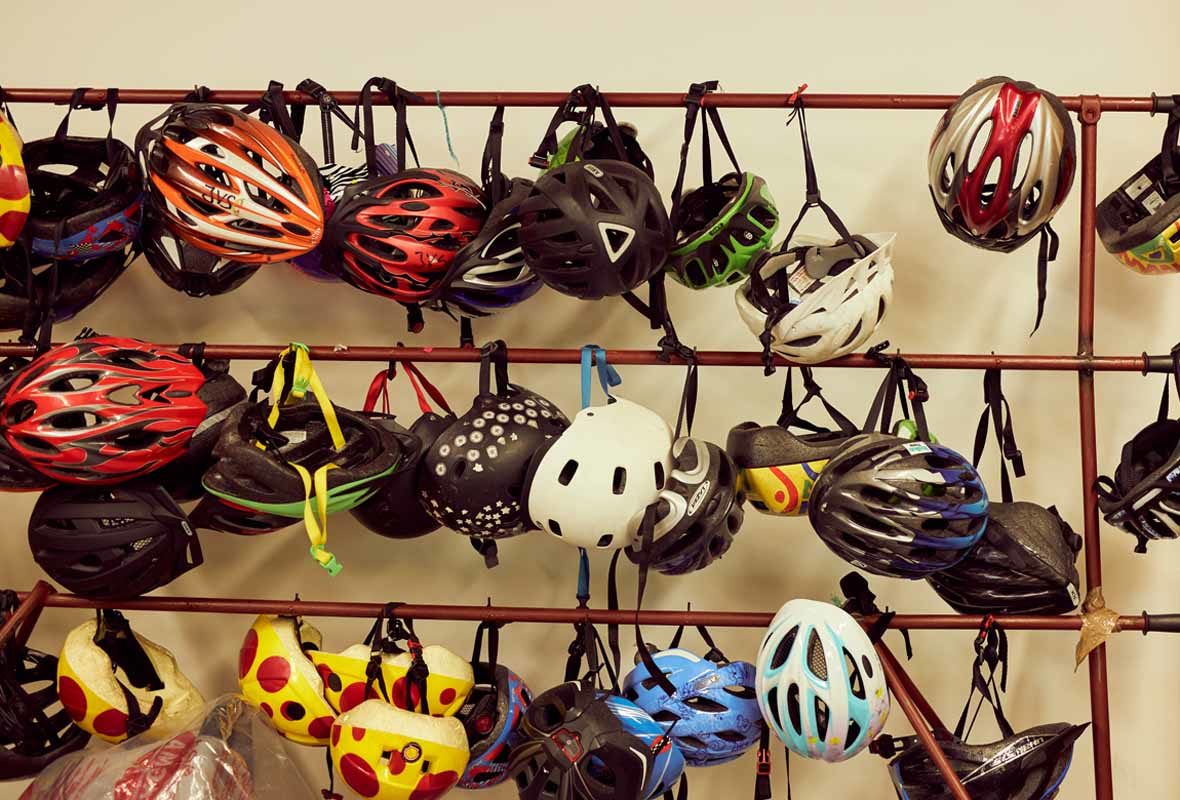 Foto: Viele Fahrradhelme hängen an Kupferstangen
