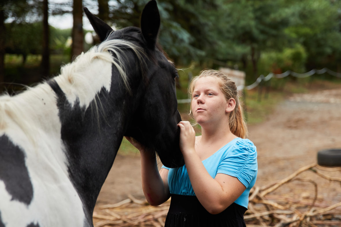 Foto: Ein Mädchen steht vor einem Pferd und streichelt es.