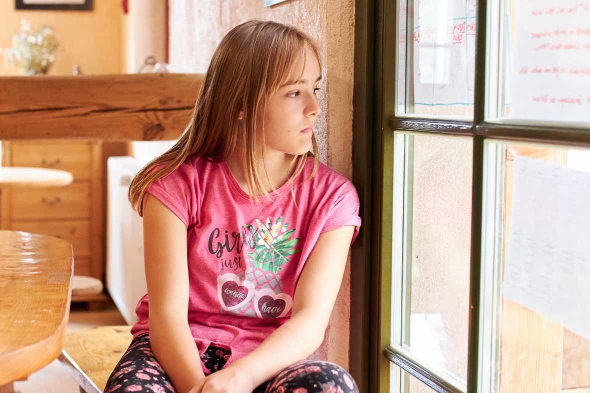 Foto: Eine Mädchen sitzt am Fenster und schaut raus