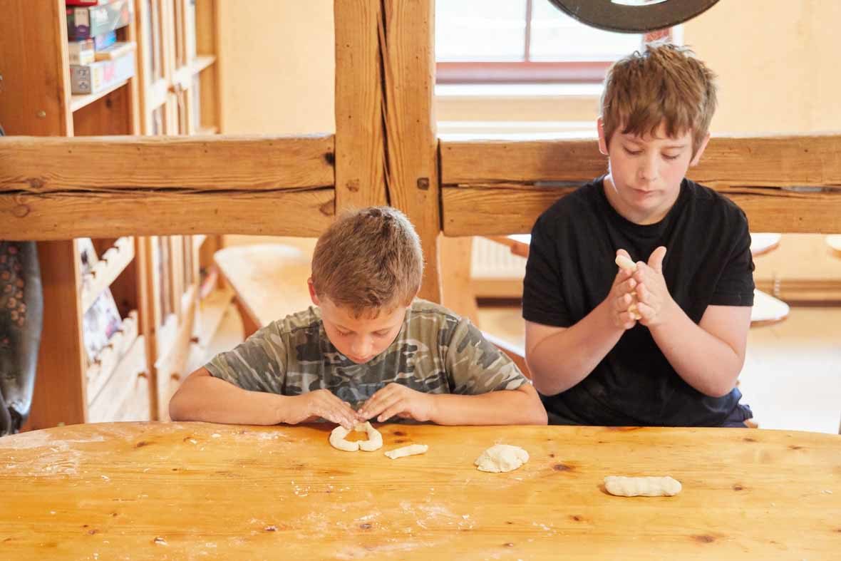 Foto: Zwei Jungen form am Tisch kleine Teigstränge