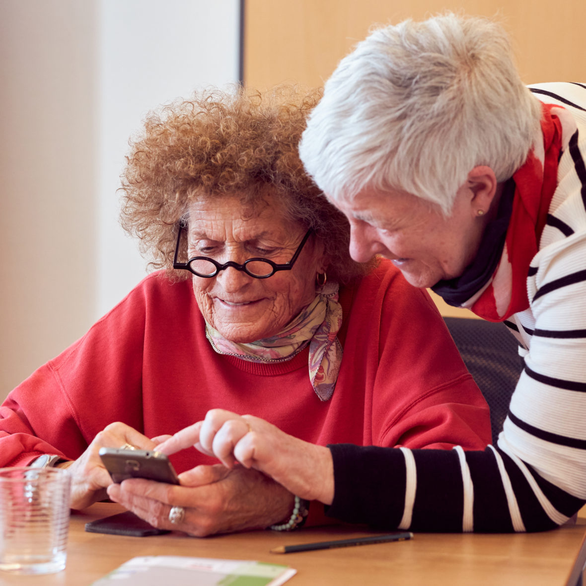 Zwei Seniorinnen schauen auf ein Smartphone.