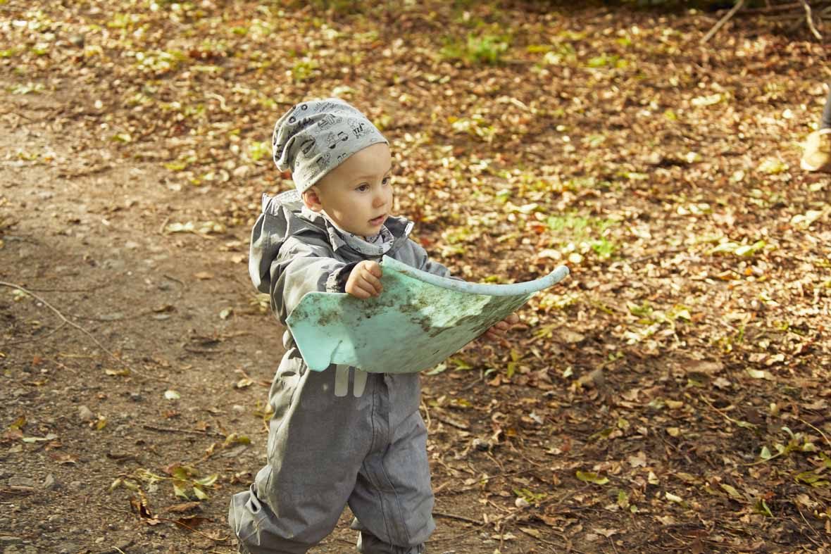 Foto: Ein Kleinkind läuft mit einer Karte in der Hand über einen Waldweg.