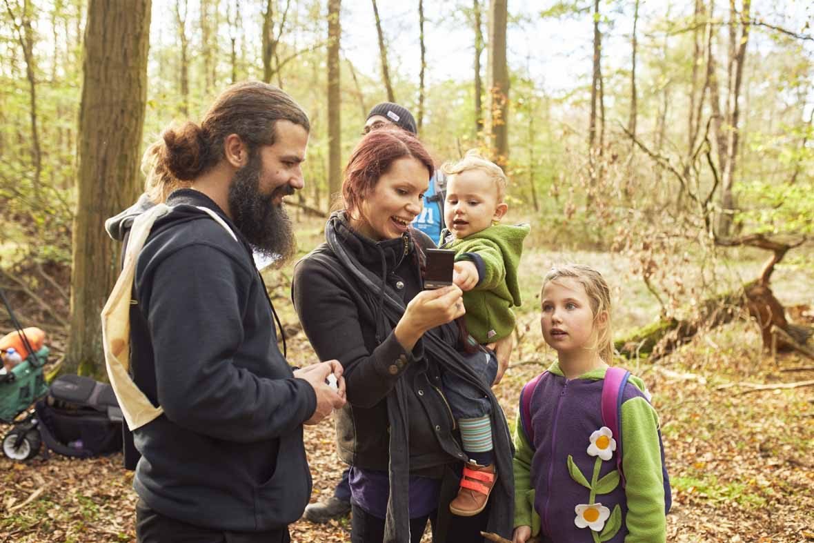 Foto: Eine Familie mit zwei Kindern schaut sich ein Polaroidfoto an.