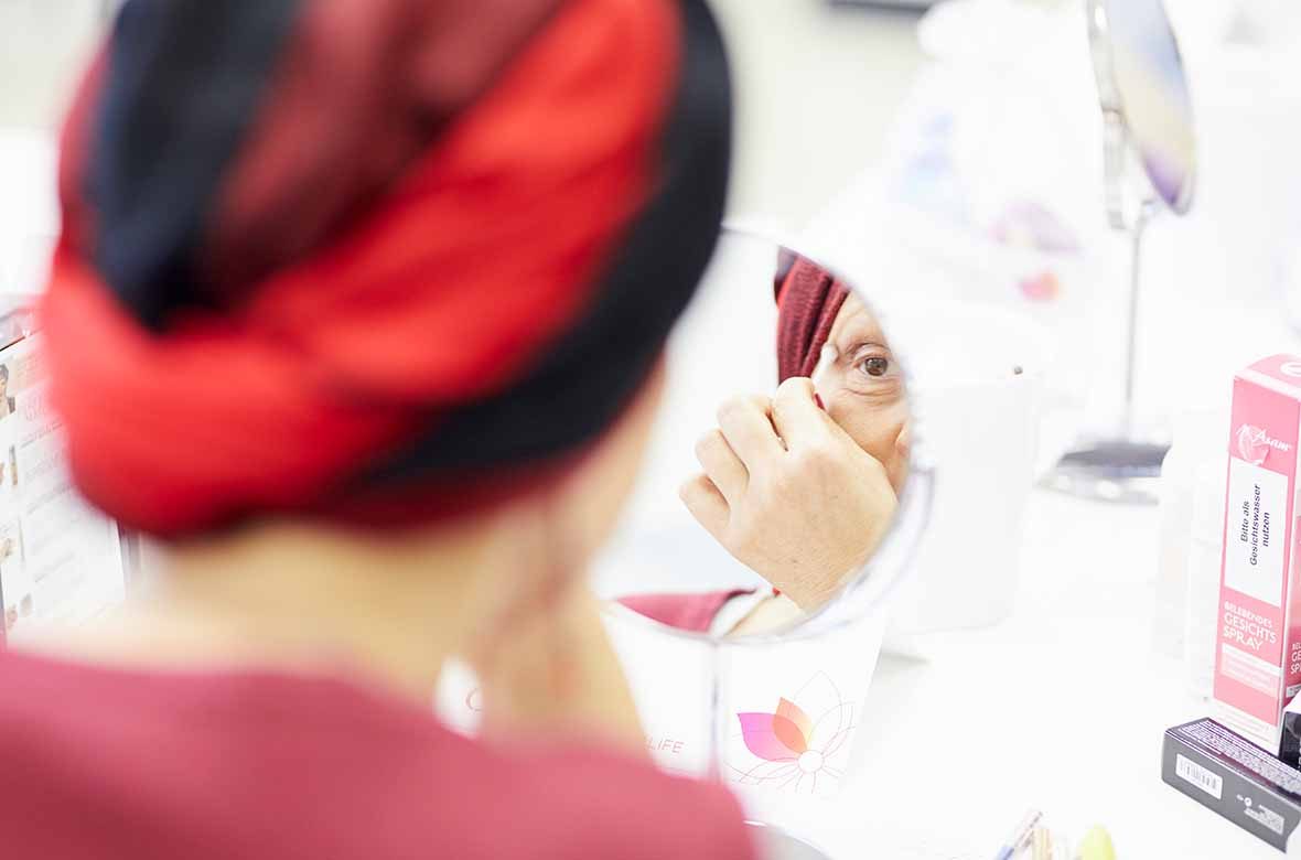 Foto: Eine Frau mit Turban schaut in einen Schminkspiegel.
