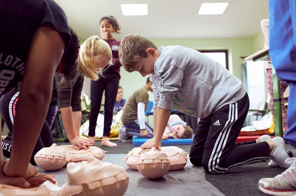 Schüler führen eine Herzdruckmassage an Puppen durch