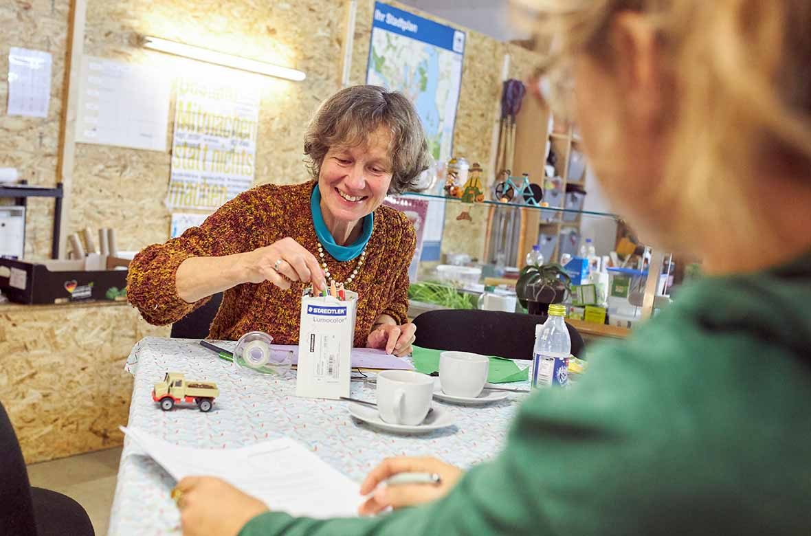 Eine Frau sitzt am Tisch und trinkt Kaffee