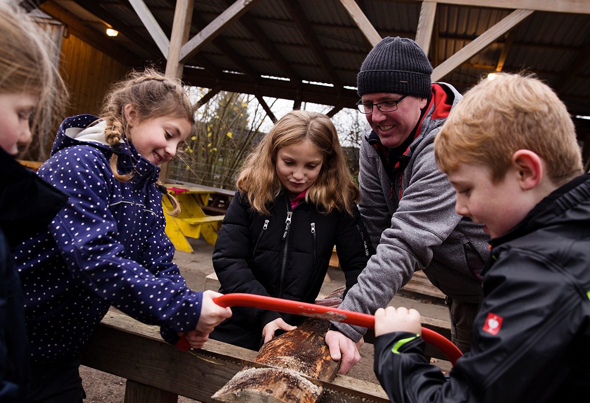 Kinder sägen ein Stück Holz.