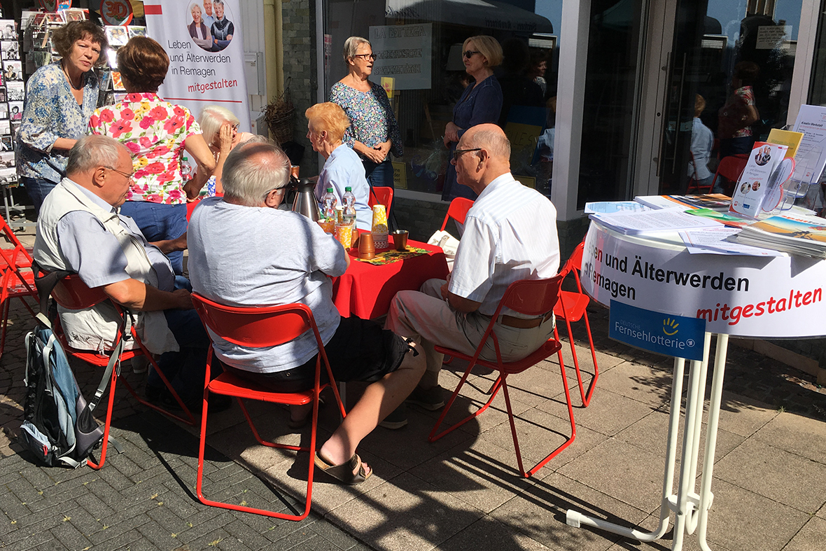 Menschen sitzen Auf Klappstühlen in der Sonne und trinken Kaffee