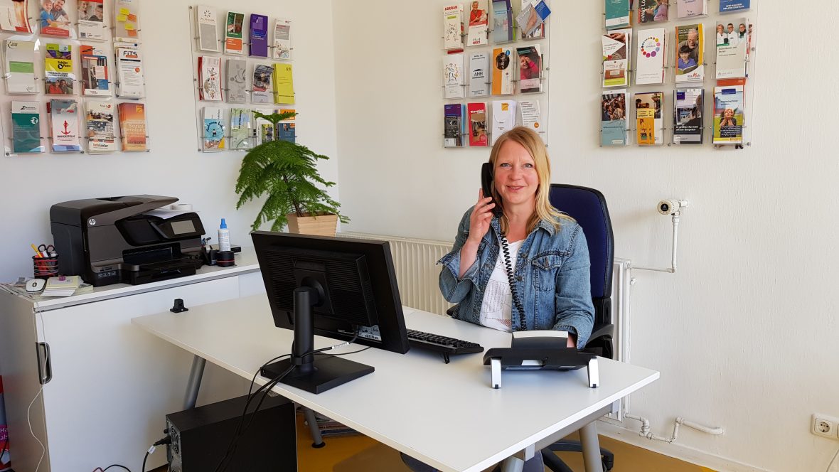 Eine Frau sitzt am Schreibtisch und telefoniert.