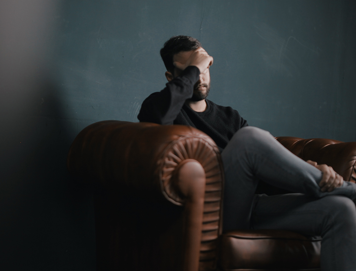 Ein Mann sitzt auf einem Sofa und schaut bedrückt